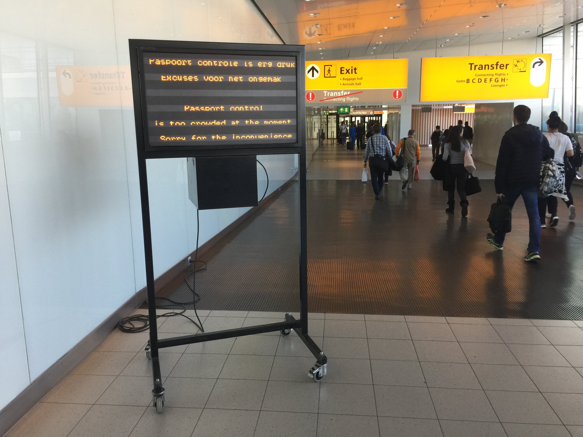 Airport hall with movable sign that warns about crowded passport control and apologizes for this