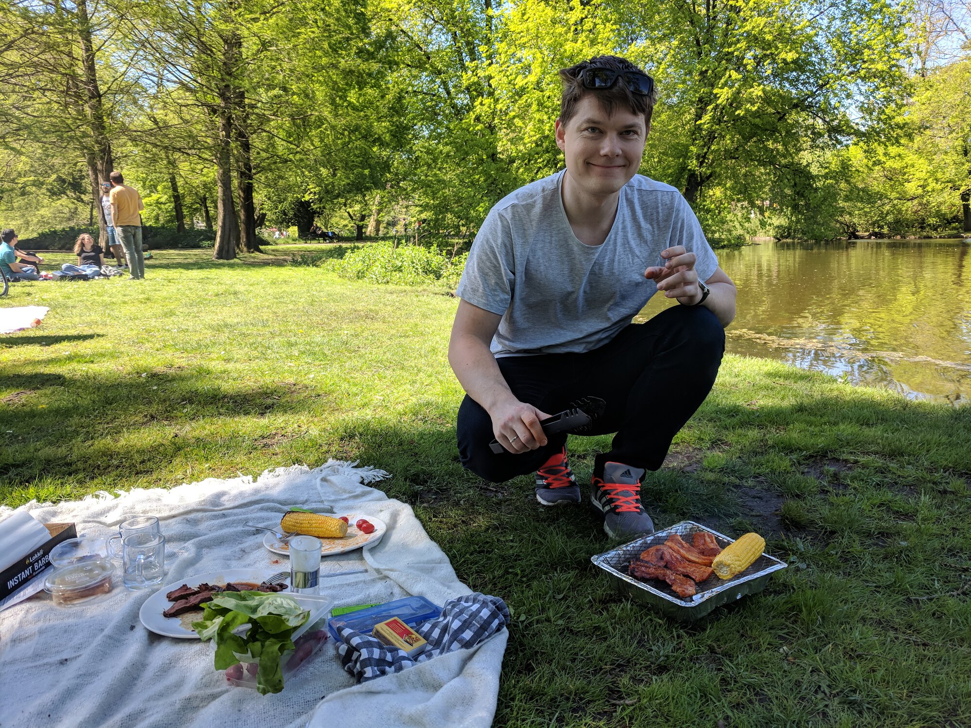 Dima smiling while making meat and corn on grill