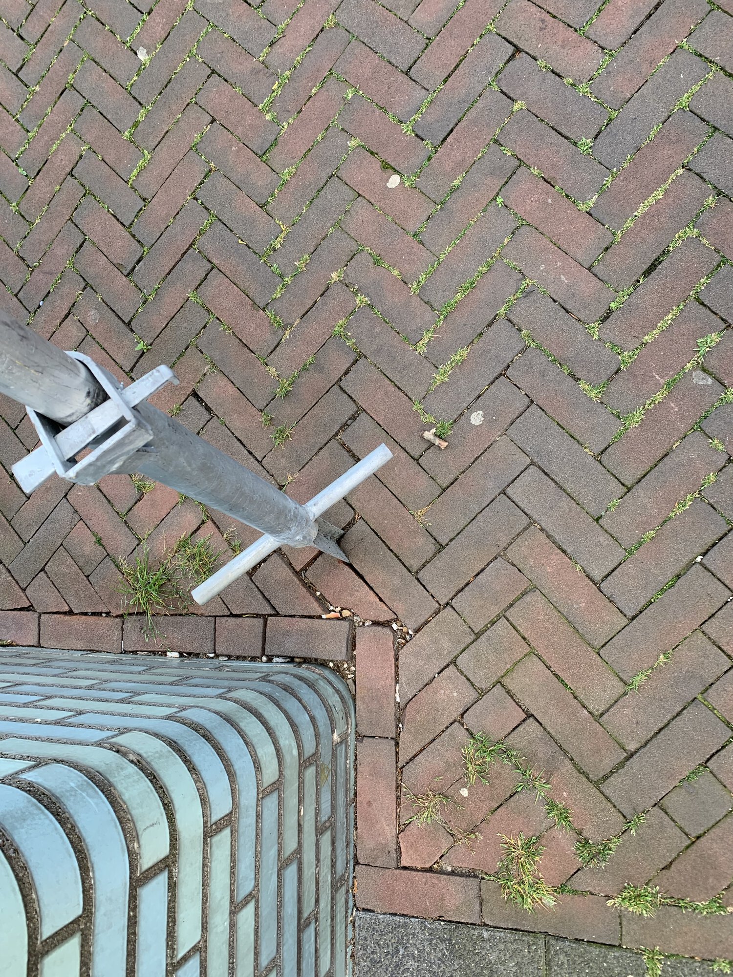 A closer look at how the sign is inserted between the tiles on a sidewalk